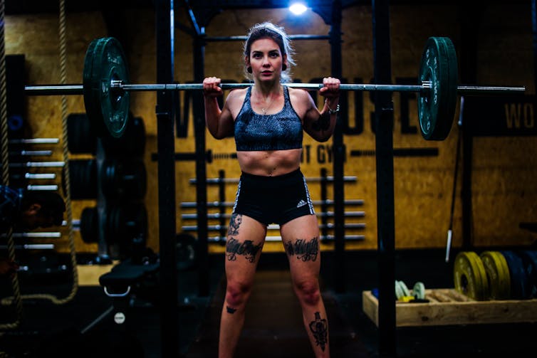 A woman gets ready to squat with a heavy weight bar.