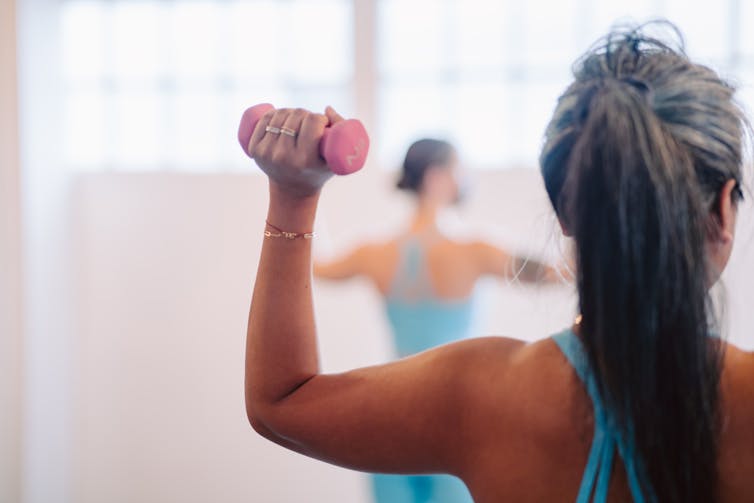 A woman lifts a small handweight in a barre class