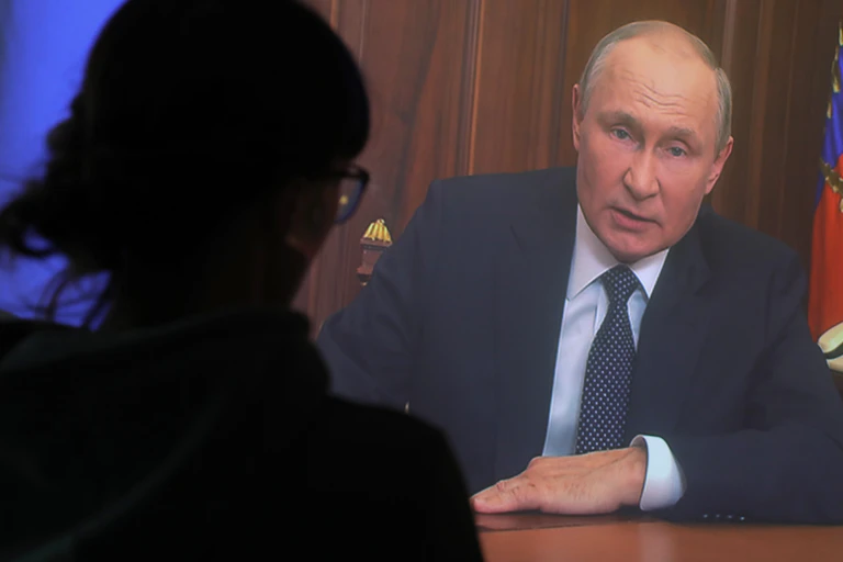 The silhouette of a woman watching Vladimir Putin on television