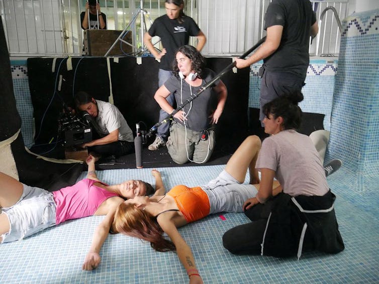 Una directora de cine dirige el rodaje de una secuencia con las actrices tumbadas en el suelo.