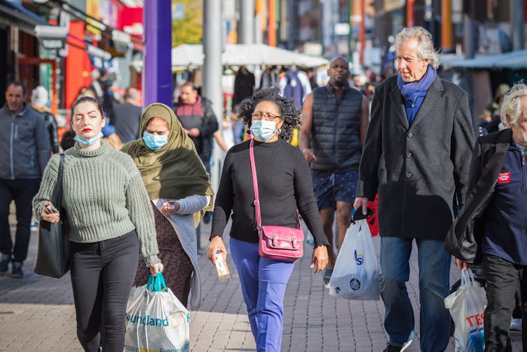 People shopping at a market in London, some wearing face masks.