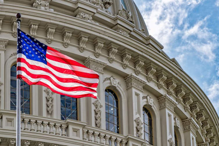 A US flag in front of the US Capitol building.