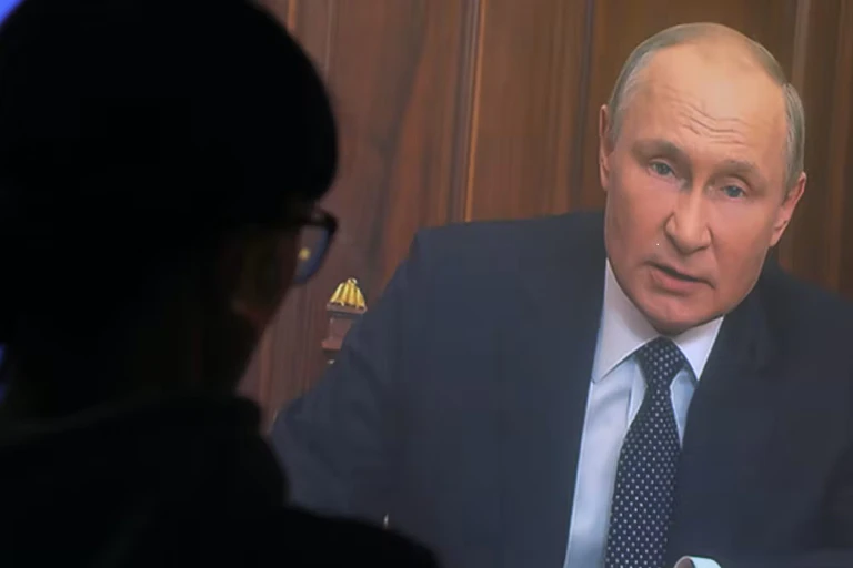 La silueta de una mujer viendo a Vladimir Putin en la televisión