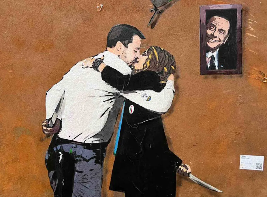 Peinture murale représentant un baiser entre Matteo Salvini et Giorgia Meloni sous l'oeil de Silvio Berlusconi