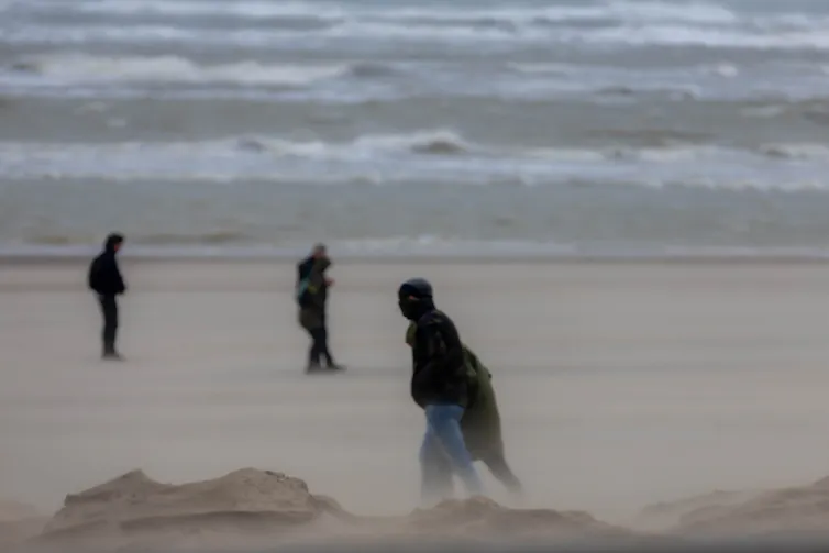 People silhouetted against stormy seascape.