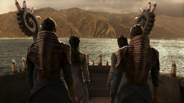 Cuatro personas en un barco miran hacia una isla verde al fondo.