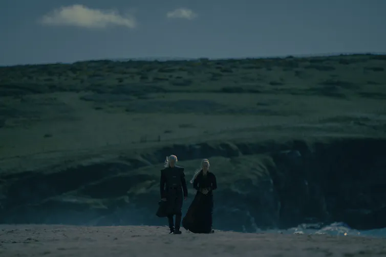 Dos personas caminan por un paisaje al amanecer.