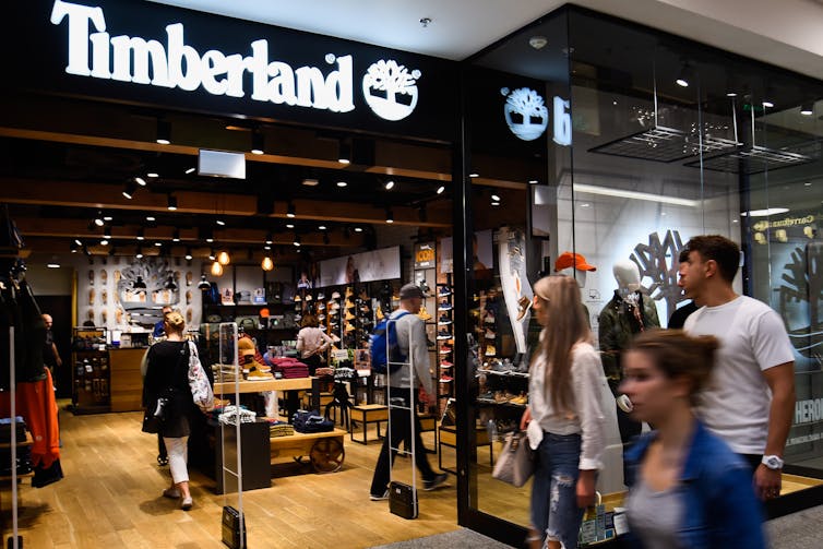 People walk past a Timberland store