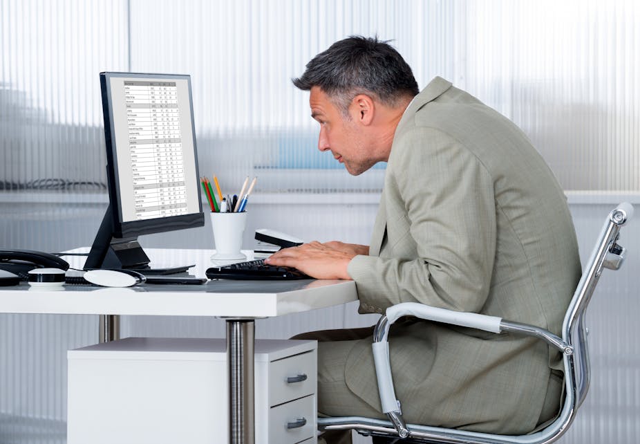 Un homme se tient tout voûté devant son ordinateur, à son bureau