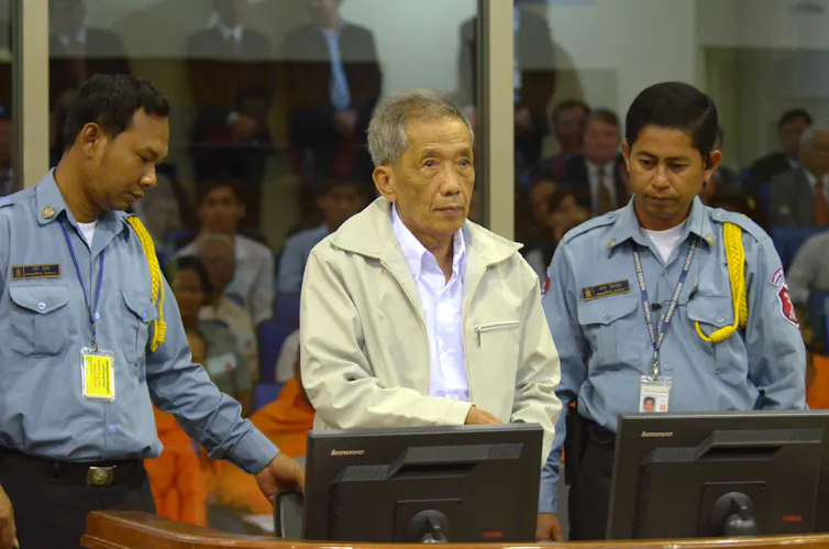 Former Khmer Rouge S-21 prison commander Kaing Guek Eav, also known as Duch, center, stands in a courtroom for a session of U.N.-backed tribunal in Phnom Penh, Cambodia.