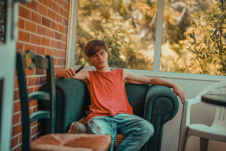 Teen or young adult sitting in armchair holding vape