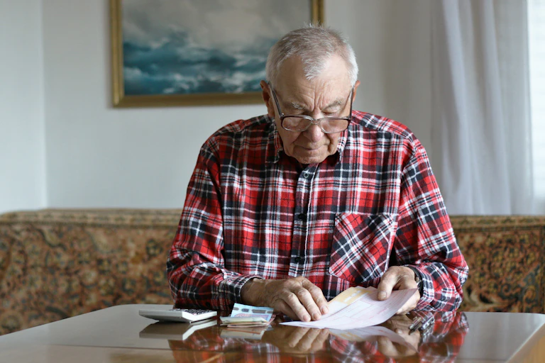 A senior man calculating bills.