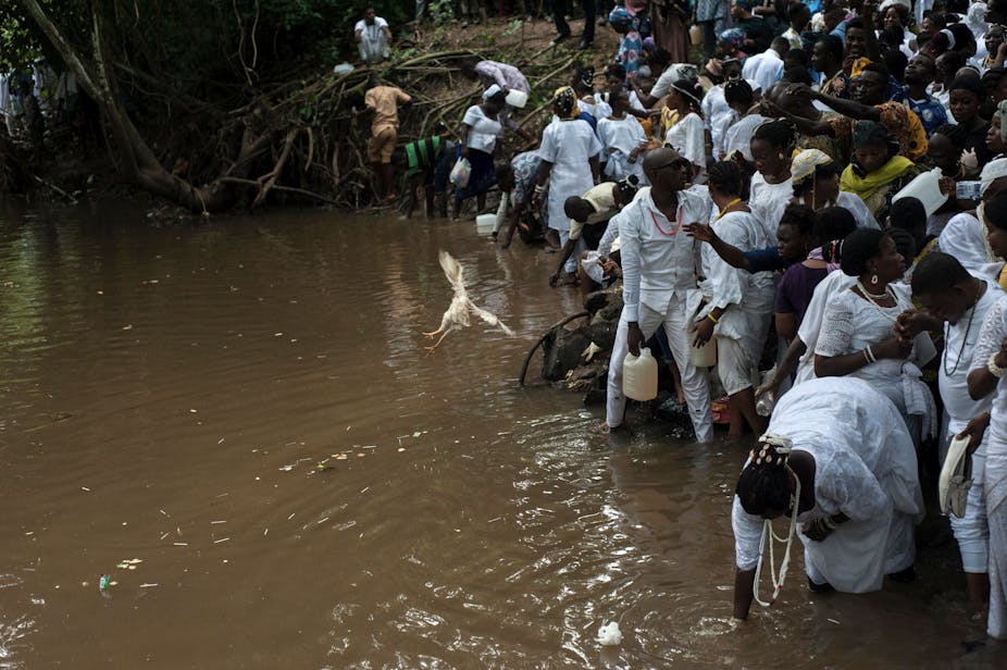 People at a river bank, fetching water or washing bodies.