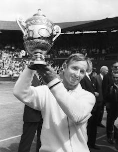 Black and white image of Australian tennis player Rod Laver holding the Wimbledon trophy.