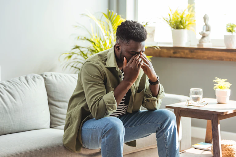 Man on sofa holding his head