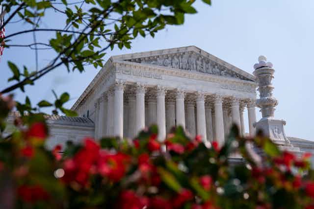 The exterior of the Supreme Court is shown,  with red flowers in front