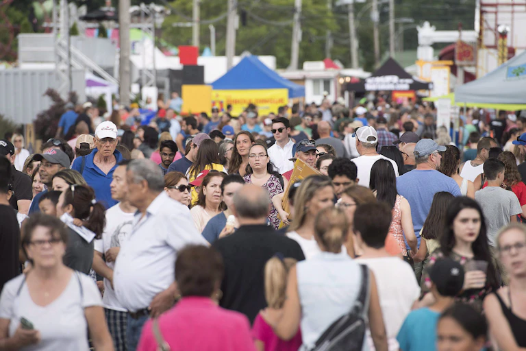 Une foule déambule sur une place, lors d'une fête, en été