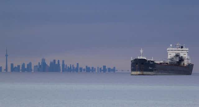 A ship sails on water with the Toronto skyline in the background