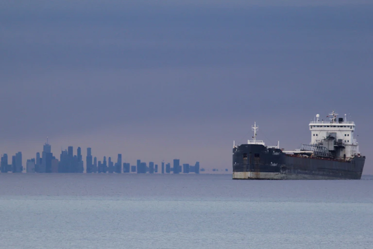 A ship sails on water with the Toronto skyline in the background