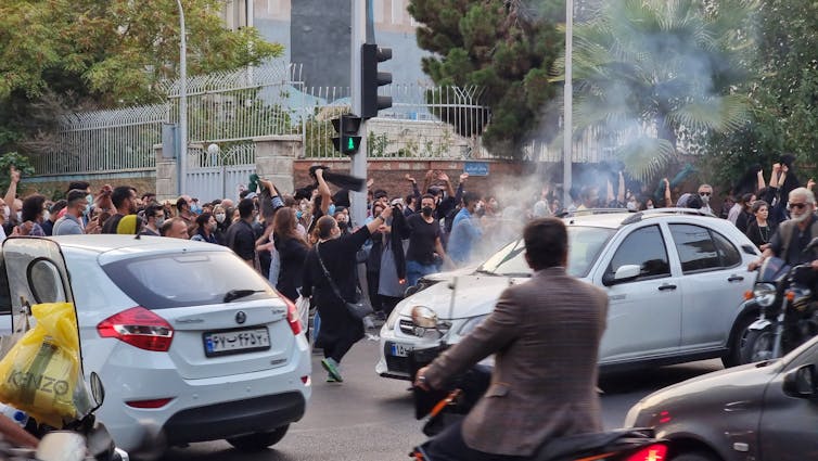 Several cars are unable to move through thousands of demonstrators.