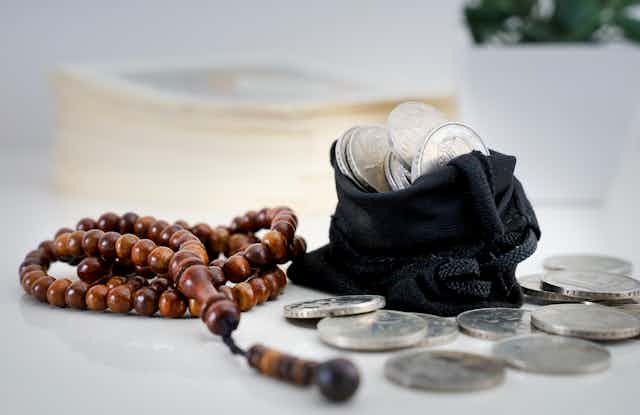 a photograph of a rosary and a bag of silver coins
