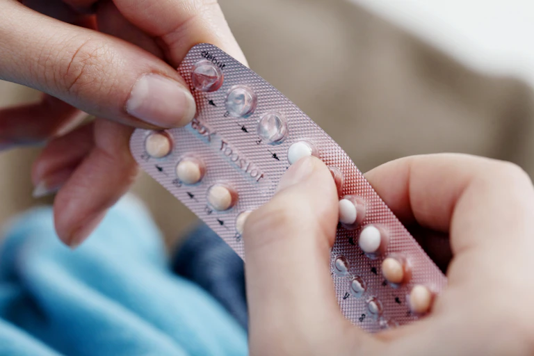 A women holds a blister pack of birth control pills.