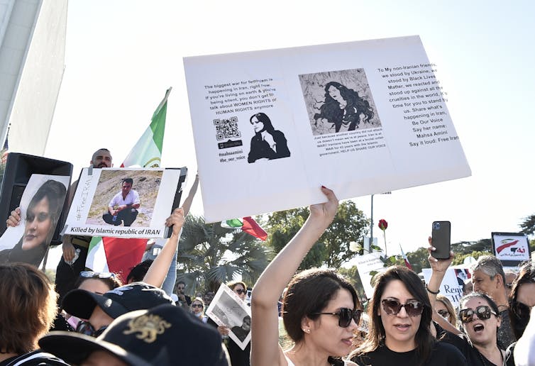 A protestor in California holds a sign with the image of the 22-year-old Iranian woman who died in Iranian police custody.