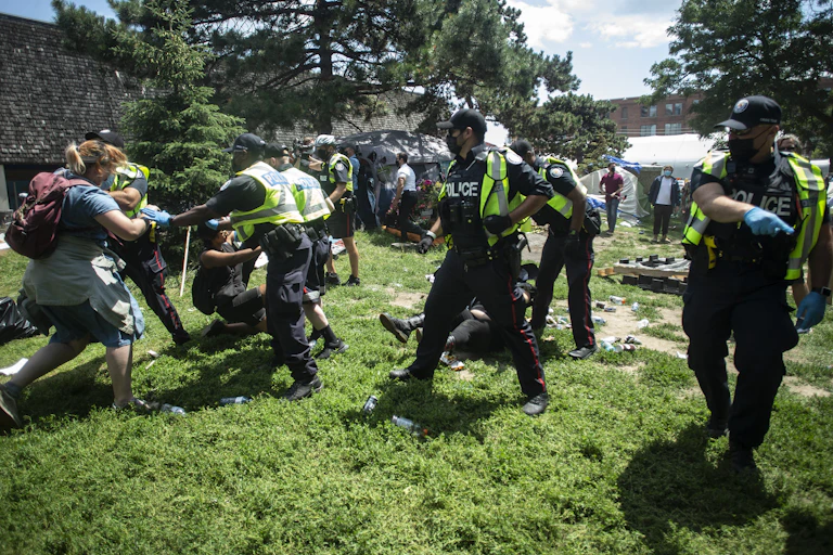 Police and protesters fight in a park.