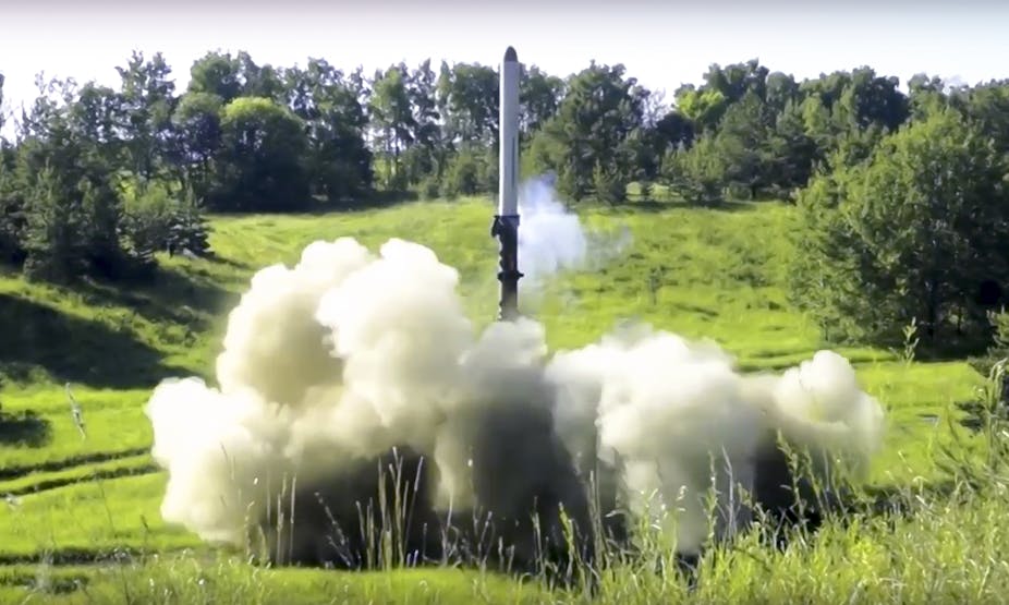 ракета вертикально ориентирована над облаком выхлопа в открытом поле