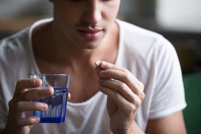 young man hold glass and pill