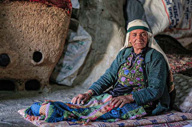 Brightly dressed woman sitting on the floor of a cave