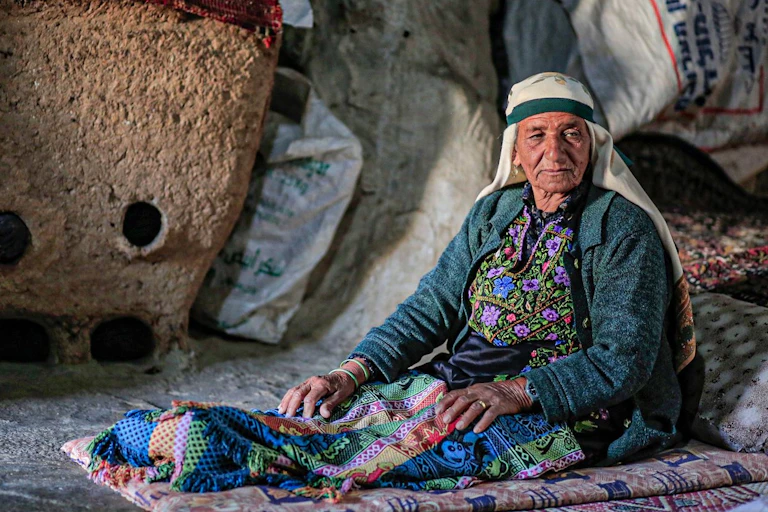 Brightly dressed woman sitting on the floor of a cave