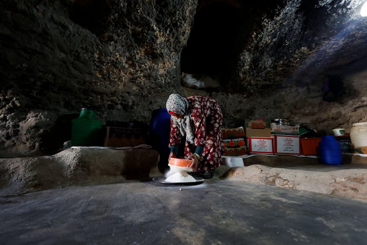 A woman sifts flour inside a cave