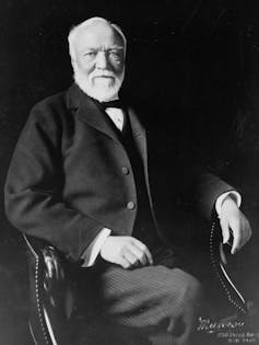 Portrait of man with white beard wearing a suit seated in a chair.