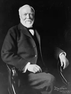 Portrait of man with white beard wearing a suit seated in a chair.
