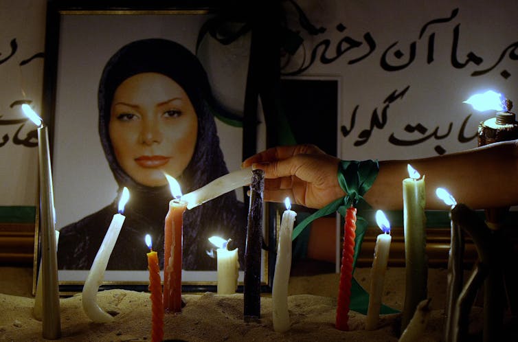 Candles lit before the photograph of a young woman in a headscarf.