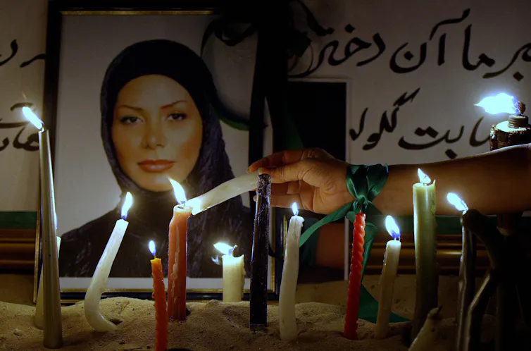 Candles lit before the photograph of a young woman in a headscarf.