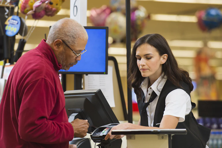 A man wearing glasses pays for groceries.