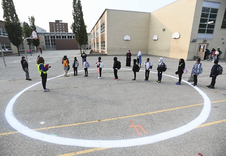 Children stand in a line in a schoolyard.