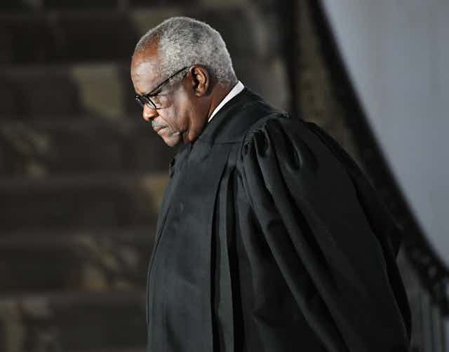 A middle-aged black man wearing a judicial robe has his head down in thought.