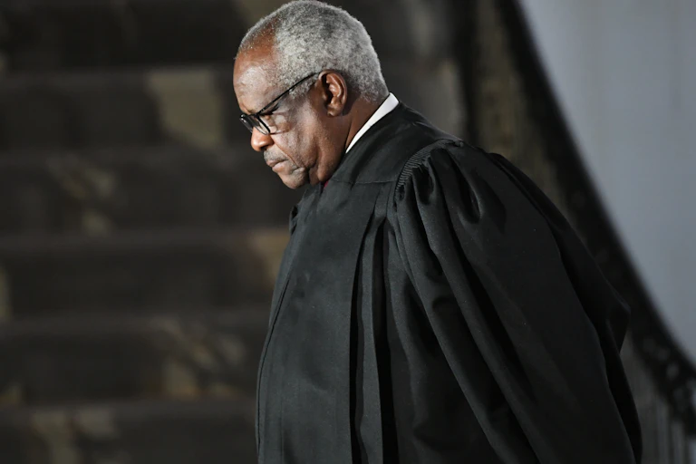A middle-aged black man wearing a judicial robe has his head down in thought.