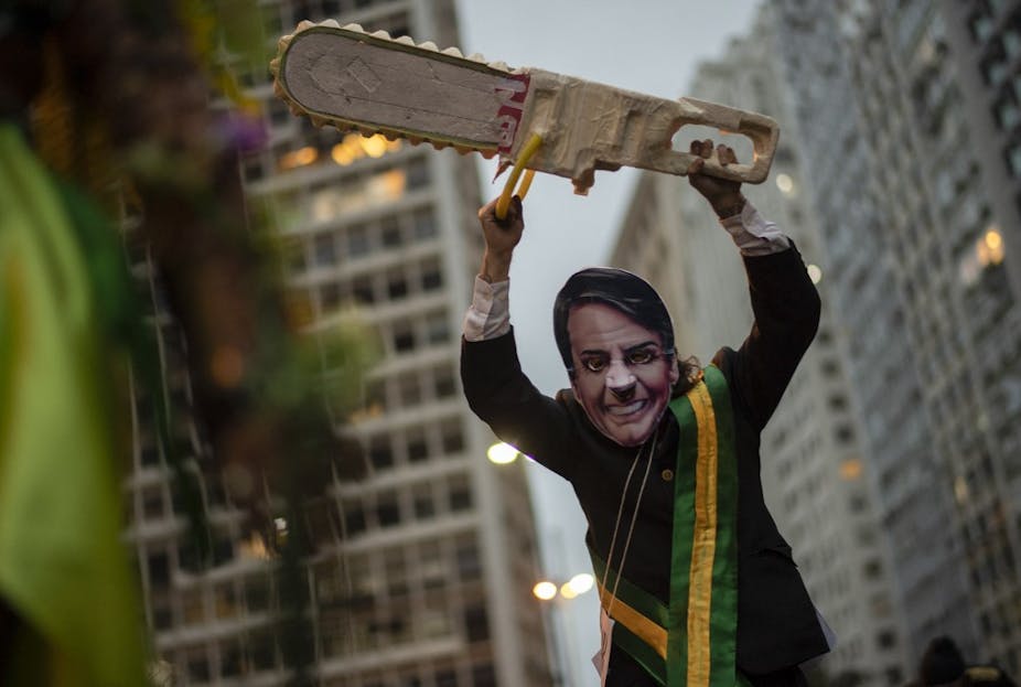Homme déguisé en Jair Bolsonaro bradissant une tronçonneuse