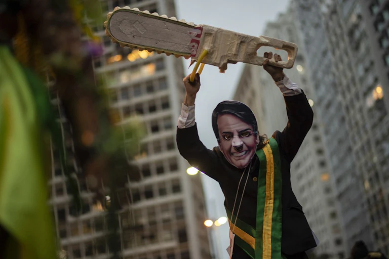 Homme déguisé en Jair Bolsonaro bradissant une tronçonneuse