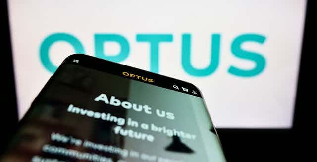 Blue on white Optus logo with a smartphone screen in the foreground