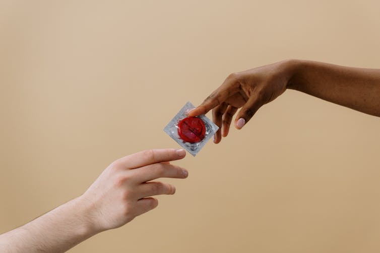 two hands passing condom