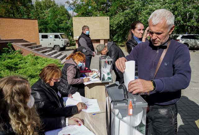 A man casts a vote in a referendum on the joining of Russian-controlled regions of Ukraine to Russia, at an outdoor polling station in Mariupol, eastern Ukraine, 25 September 2022