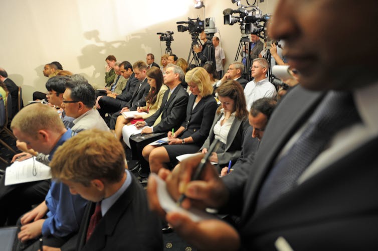 A group of journalists sitting in rows at a press conference.