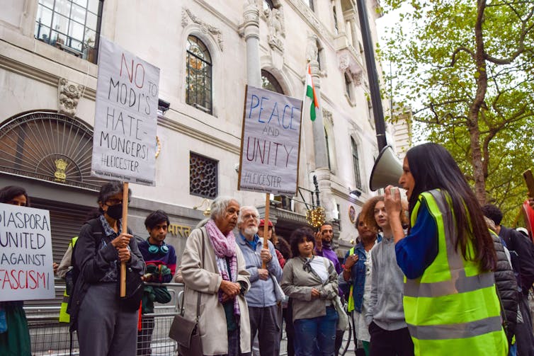 Protestors hold up posters on a street corner.