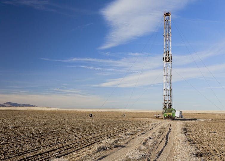A lone fracking rig in an empty brown field.