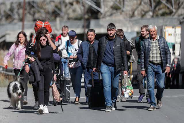 Russian men and women with their luggage walk along a road after passing through customs at the Georgia-Russia border, September 2022